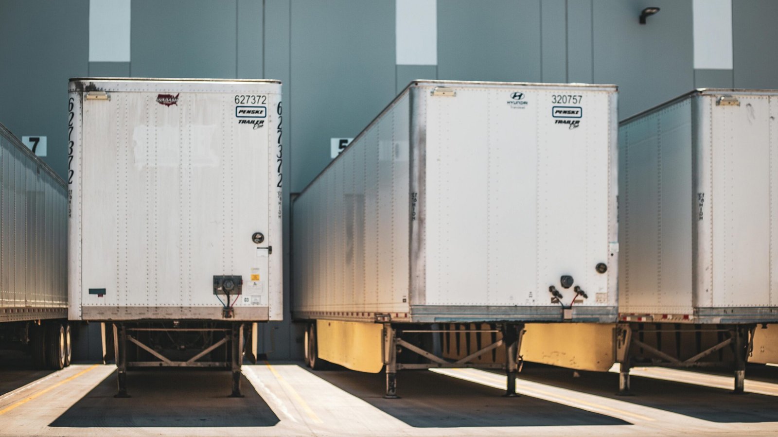 service-3 A row of freight trailers parked at a commercial loading dock, emphasizing transportation and logistics.
